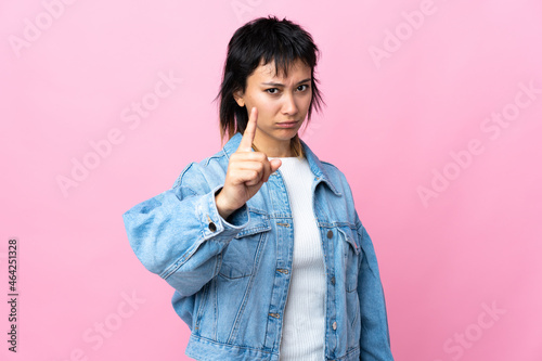 Young Uruguayan woman over isolated pink background counting one with serious expression