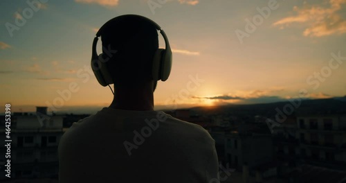 Sagoma di un ragazzo al tramonto con cuffie photo