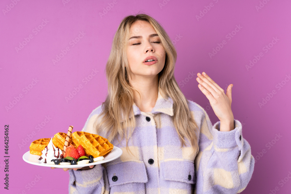 Teenager Russian girl holding waffles isolated on purple background with tired and sick expression Teenager Russian girl holding waffles isolated on purple background with tired and sick expression