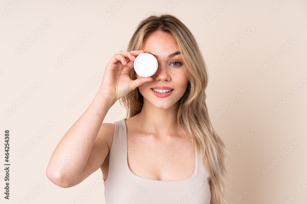 Teenager blonde girl with moisturizer over isolated background Teenager blonde girl with moisturizer over isolated background