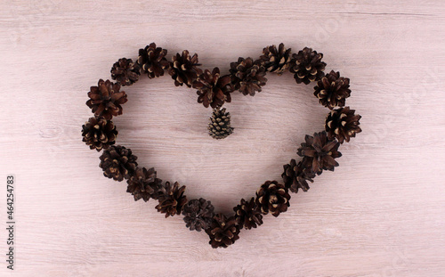 Heart laid out of cones on a wooden background