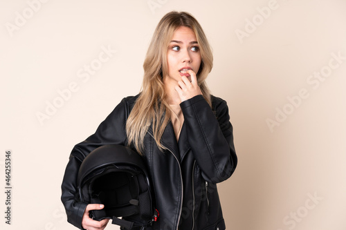 Russian girl with a motorcycle helmet isolated on beige background nervous and scared © luismolinero