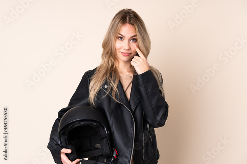 Russian girl with a motorcycle helmet isolated on beige background showing something © luismolinero