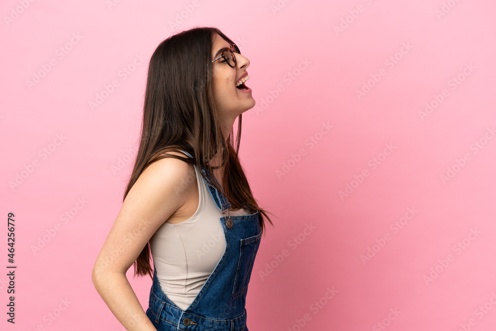 Young caucasian woman isolated on pink background laughing in lateral position Young caucasian woman isolated on pink background laughing in lateral position