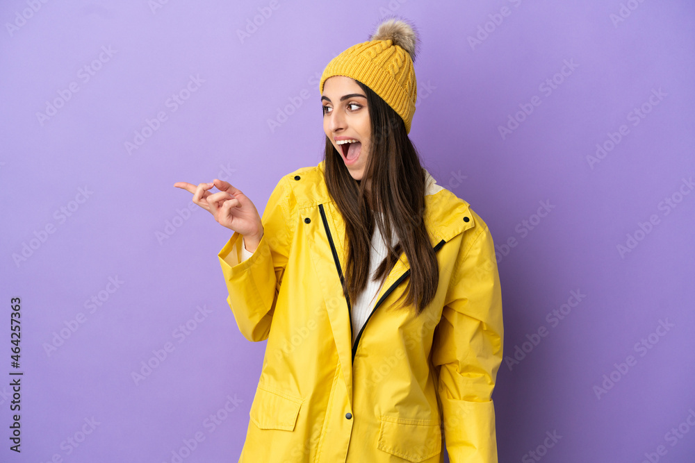Young caucasian woman wearing a rainproof coat isolated on purple background intending to realizes the solution while lifting a finger up Young caucasian woman wearing a rainproof coat isolated on purple background intending to realizes the solution while lifting a finger up