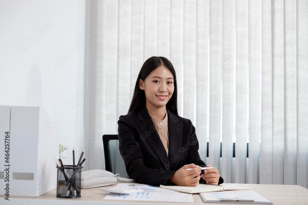 Asian businesswomen sit at their desks and calculate financial graphs showing results about their investments, plan a successful business growth process in the office Asian businesswomen sit at their desks and calculate financial graphs showing results about their investments, plan a successful business growth process in the office