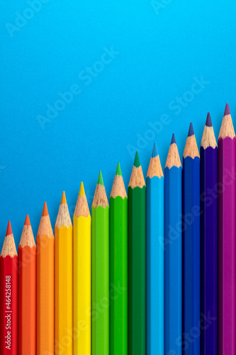 Colour pencils arranged diagonally on a blue vertical paper background.