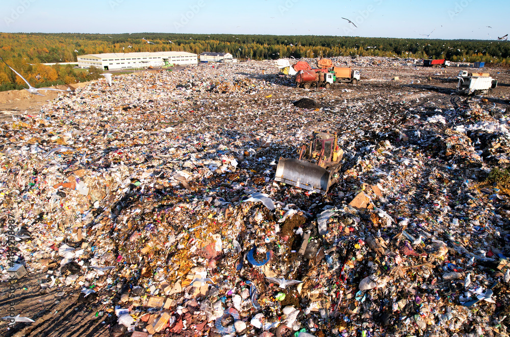 Landfill waste disposal. Garbage dump with waste plastic and polyethylene. Bulldozer at landfill working on rubbish disposal. Reduce greenhouse gas emissions and methane emissions.