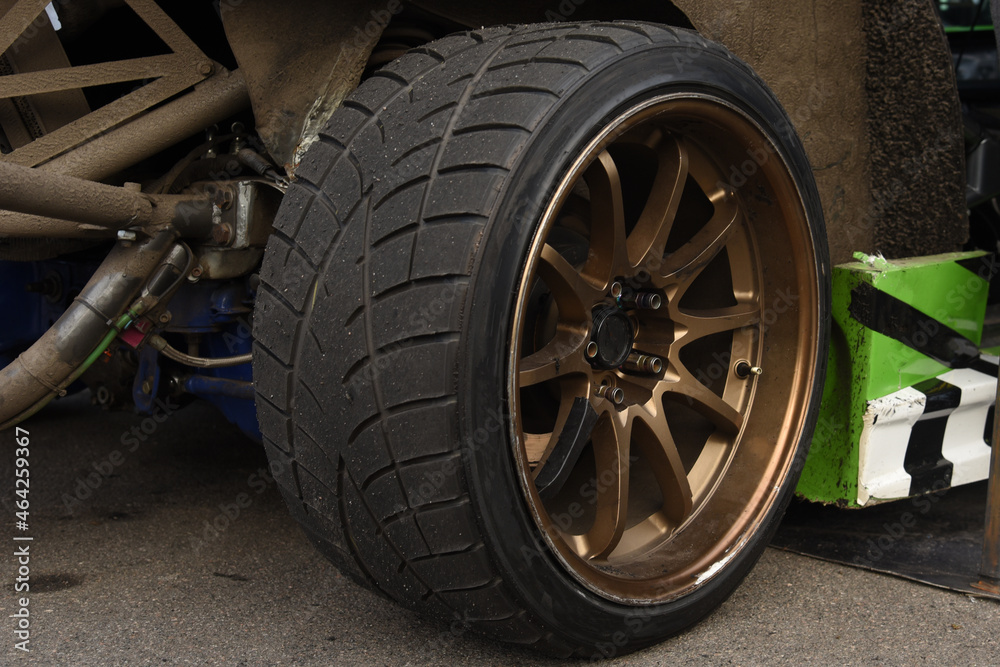 Tires of race car for driving. Drag and drift car with lower-profile tire. Racing low profile tyre with brake disc. Alloy wheel with calipers and racing brakes of the sport cars. Tyres background.