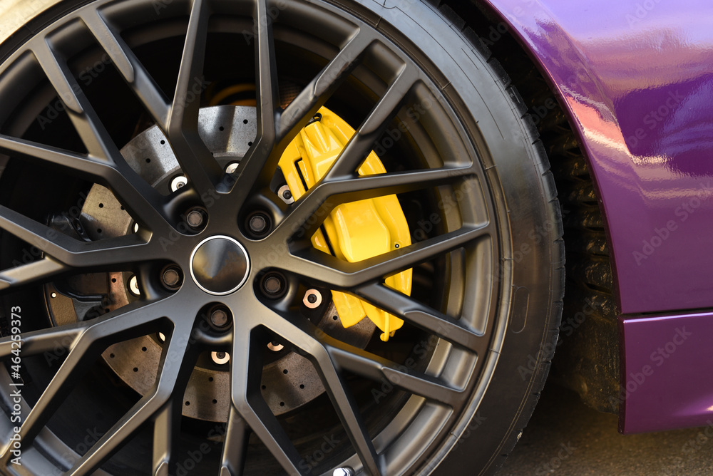 Alloy wheel with calipers and racing brakes of the sport car. Racing brake disc and low profile tyres. Race car test driving. Lower-profile tires of drag and drift cars. High-performance sports cars.