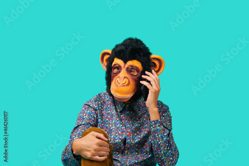Photography man wearing a monkey mask talking on the phone