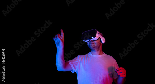 Young man using vr glasses in black background and neon light environment.