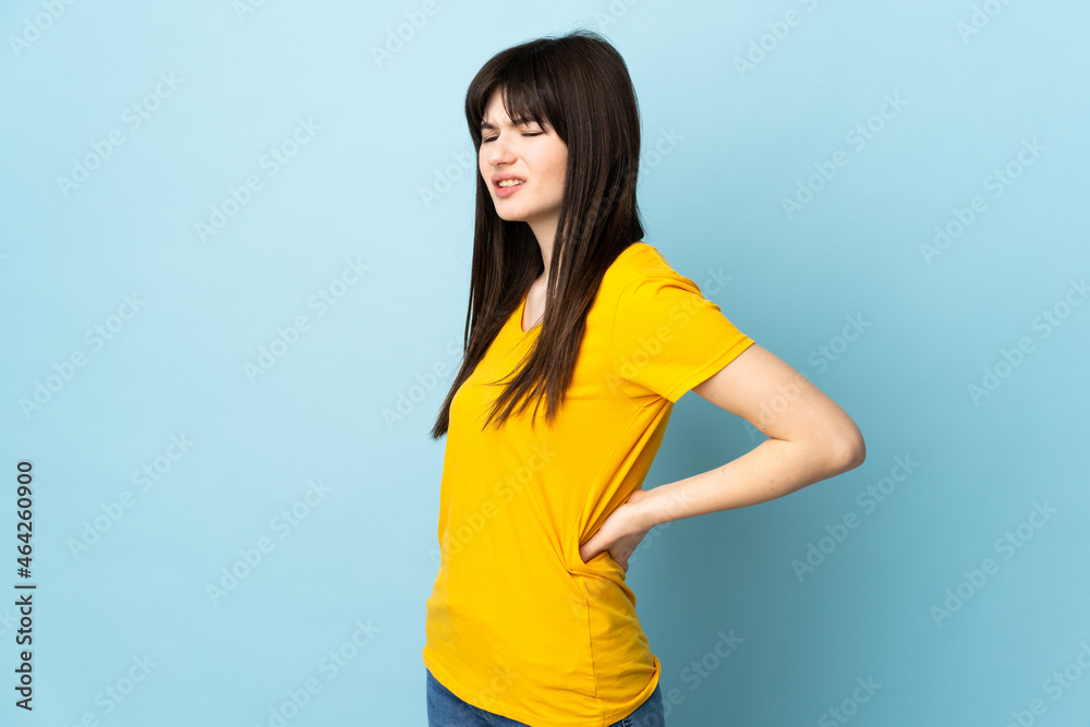 Teenager Ukrainian girl isolated on blue background suffering from backache for having made an effort Teenager Ukrainian girl isolated on blue background suffering from backache for having made an effort