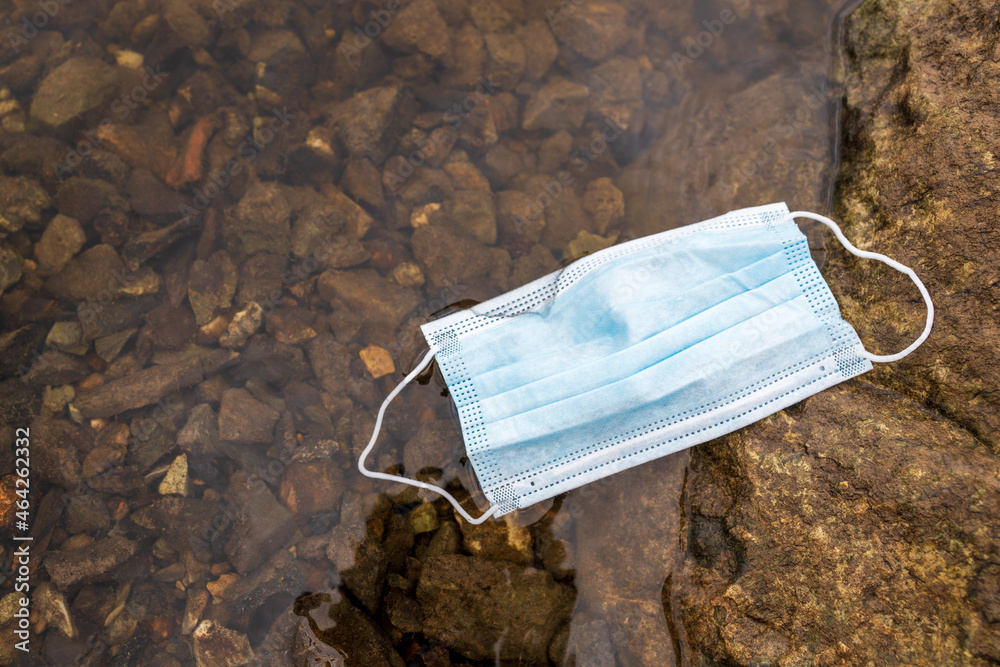 garbage in the water, medical mask on the river bank garbage in the water, medical mask on the river bank