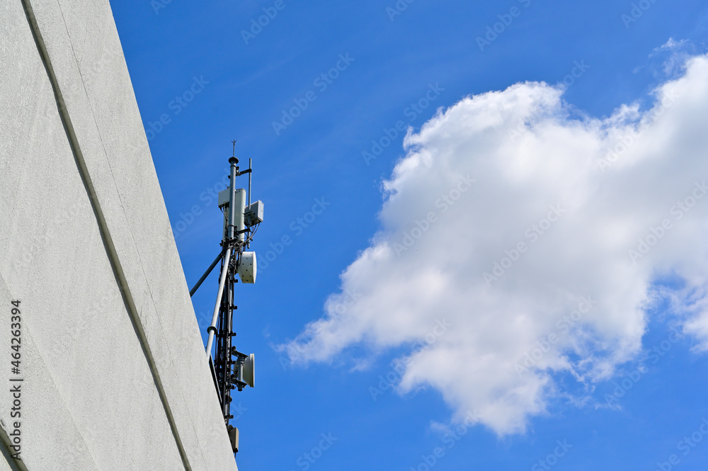 Cellphone communication tower on the roof of a building under the bright blue sky