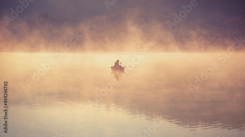 Early morning fishing on a steaming lake in October, in the golden light.