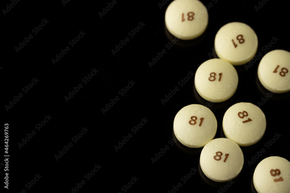 scattered low dose 81 milligrams aspirin on a black background with a low depth of field, commonly used as a preventive medicine for heart disease with copy space scattered low dose 81 milligrams aspirin on a black background with a low depth of field, commonly used as a preventive medicine for heart disease with copy space
