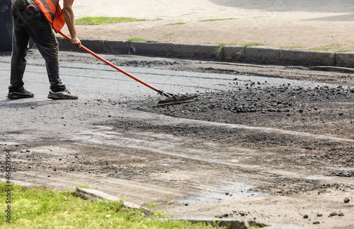 Worker laying new asphalt on city street, closeup. Road repair service