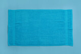 Soft beach towel on light blue background, top view