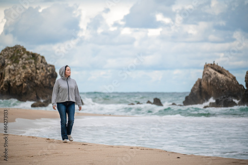 Portrait of happy caucasian woman in jeans walking running at autumn fall day outdoor on the shore beach at sunset, lifestyle natural emotion. california coast