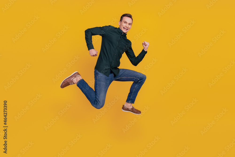 Full length profile side photo of young cheerful man have fun jump go run sale isolated over yellow color background