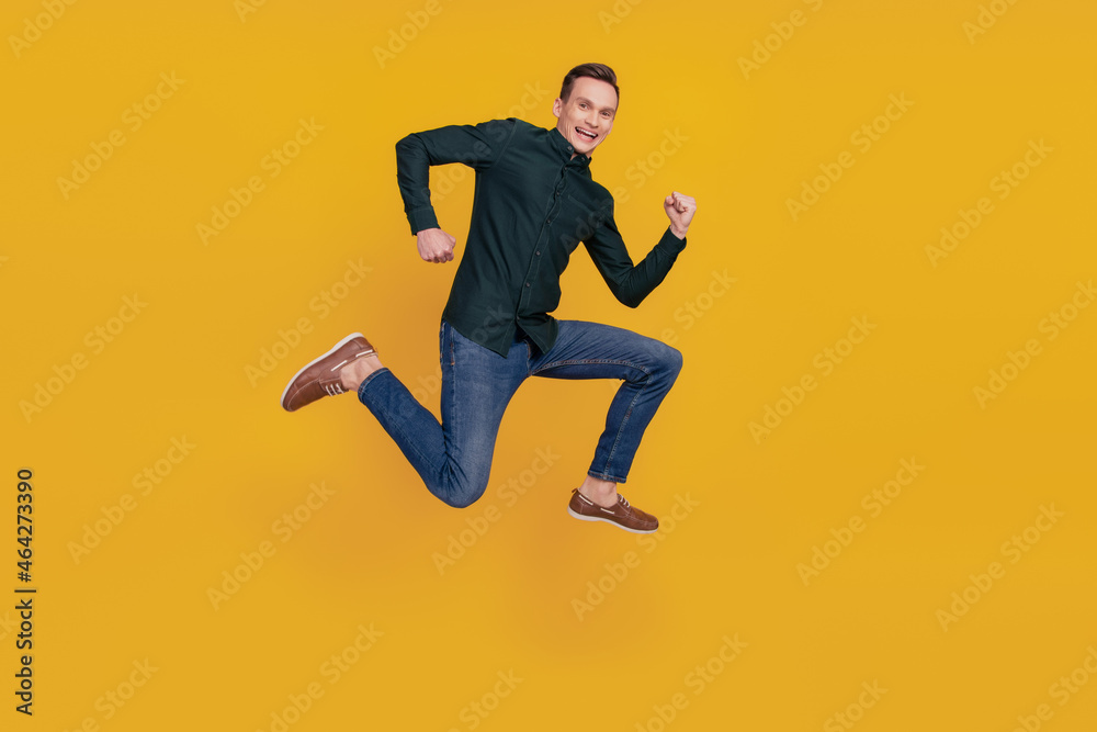 Full length profile side photo of young cheerful man have fun jump go run sale isolated over yellow color background Full length profile side photo of young cheerful man have fun jump go run sale isolated over yellow color background