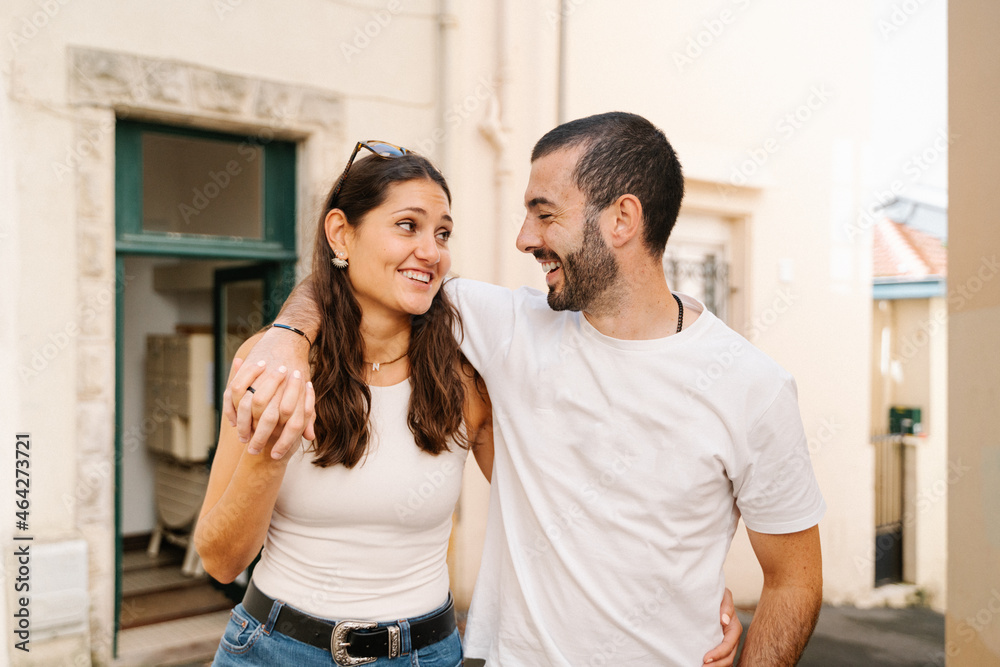 Joyful loving ethnic couple smiling while they walk down the street