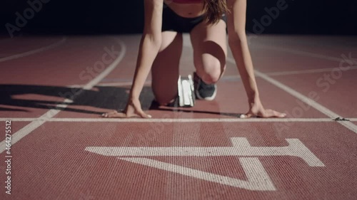 slow motion female runner at the start close-up in the dark at the stadium professional runner athletic photo