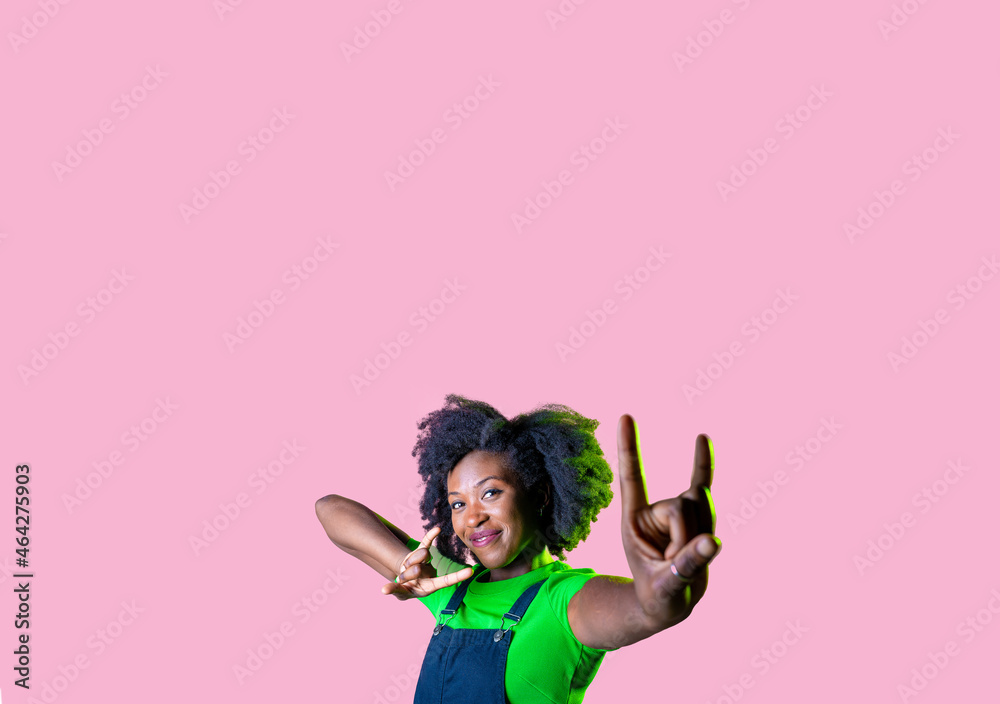 Young black woman isolated pink advertising copy space background showing a horns gesture
