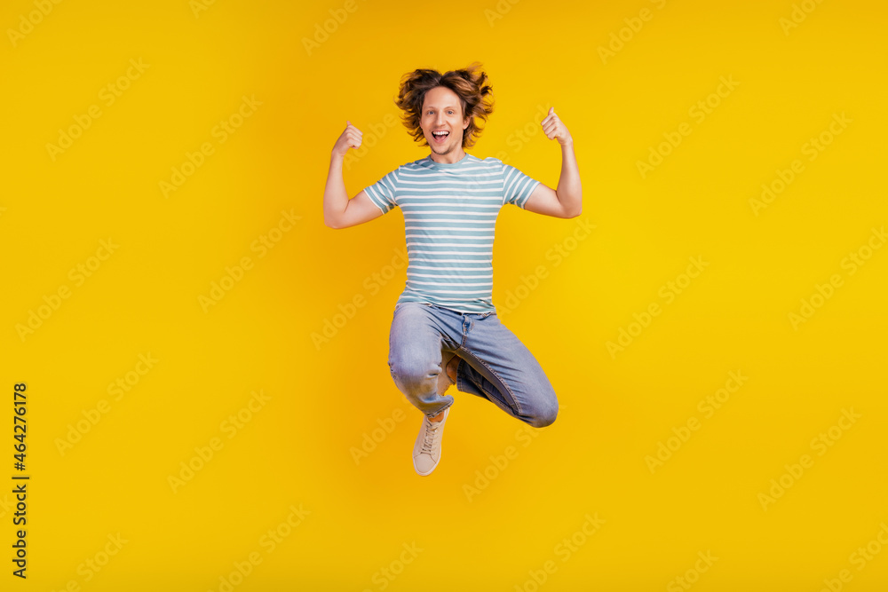 Full-body photo of young cheerful man happy positive smile jump up show thumbs-up like isolated on shine yellow background