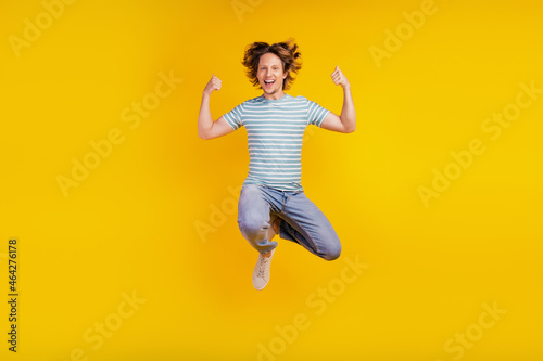 Full-body photo of young cheerful man happy positive smile jump up show thumbs-up like isolated on shine yellow background