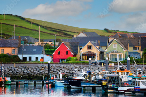 Various colorful houses and boats lining DIngle Bay in Dingle, Ireland.
