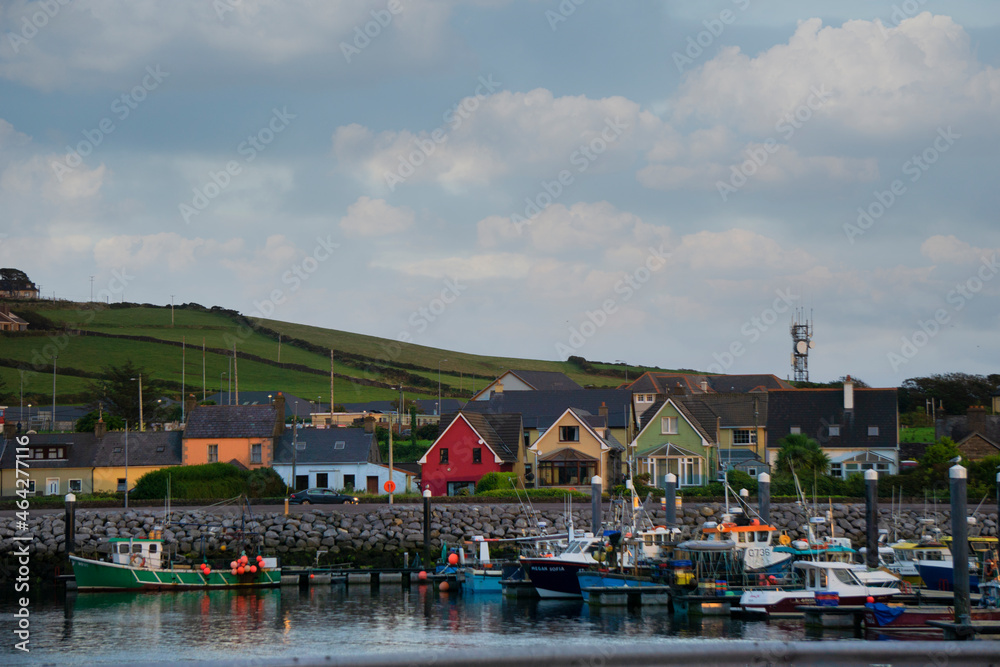 Various colorful houses and boats lining DIngle Bay in Dingle, Ireland.

