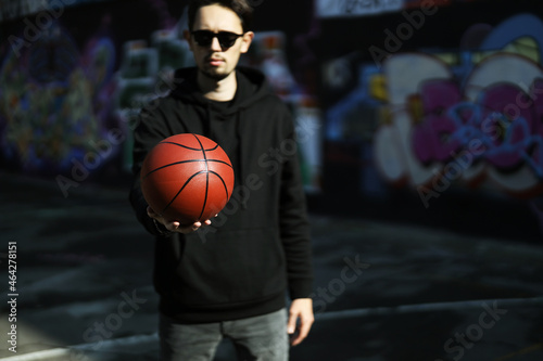 young male athlete holds a basketball ball in his hand on a street playground. boy playing basketball