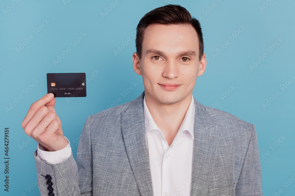 Photo of young business man happy positive smile hold credit card money income advertise isolated over blue color background Photo of young business man happy positive smile hold credit card money income advertise isolated over blue color background