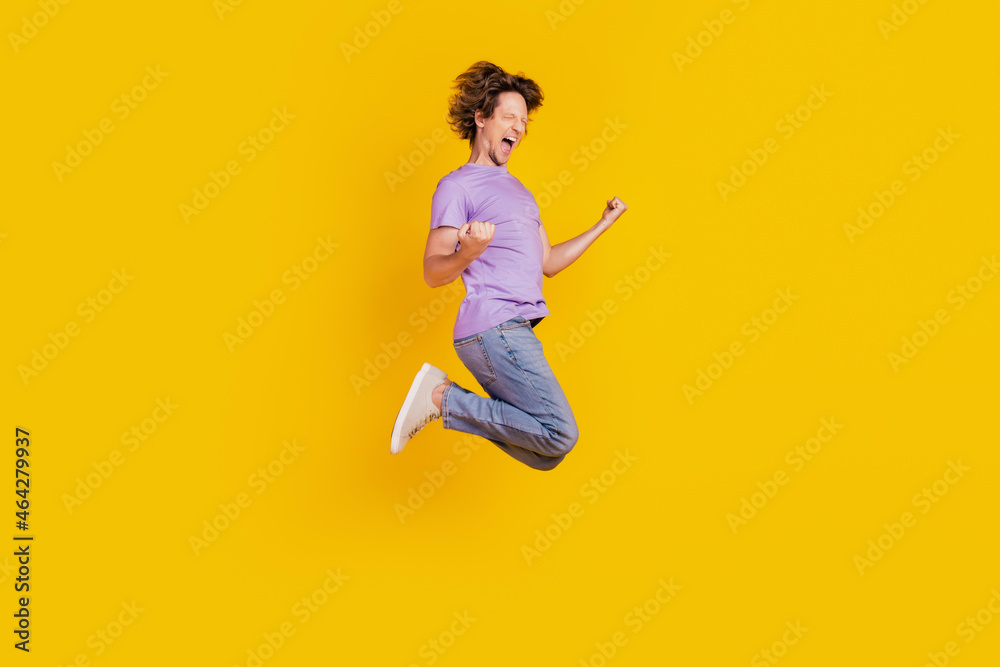 Photo of cheerful astonished man jump celebrate victory wear casual jeans clothes on yellow background