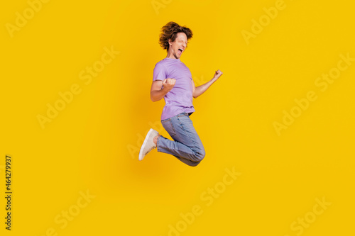 Photo of cheerful astonished man jump celebrate victory wear casual jeans clothes on yellow background © Tetiana