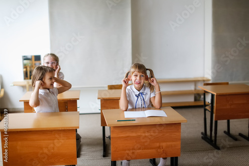 Children in class do exercises, kids pupils rub their ears and show faces, break in the lesson, dynamic pause, Concept learning, private small school, extracurricular activities
