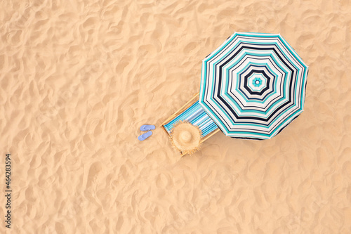 Canvas-taulu Striped beach umbrella near sunbed with vacationist's stuff on sandy coast, aerial view