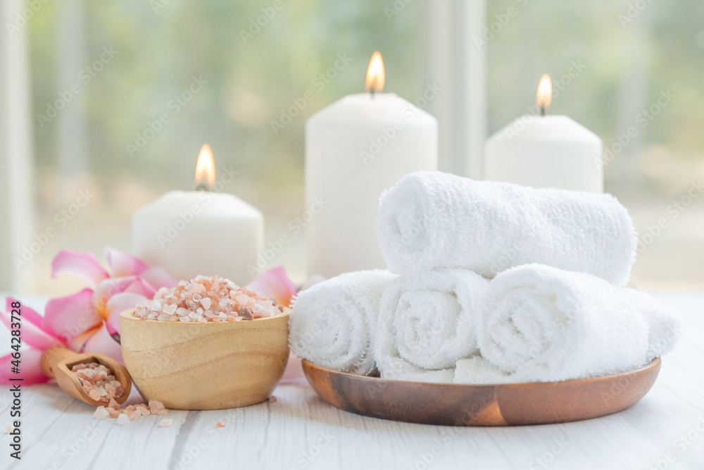 Natural relaxing spa composition on massage table in wellness center    with towels, flowers and salt, candle  on massage table in spa salon.