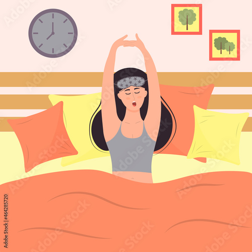 Young woman in sleeping mask is waking up and yawning. Girl is sittting in the bed with pillows. Daily morning routine.