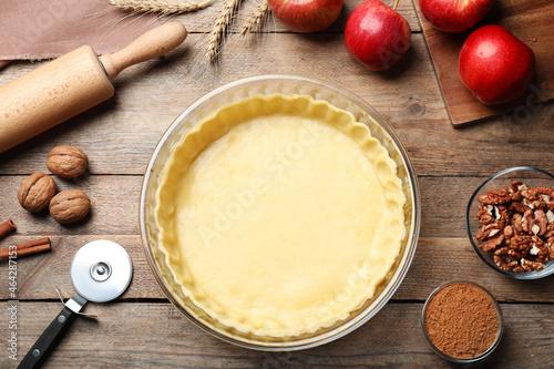Foto Flat lay composition with raw dough and ingredients for apple pie on wooden tabl