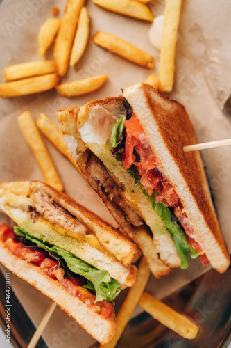 Sandwich with fresh vegetables and ham and fries on wooden board