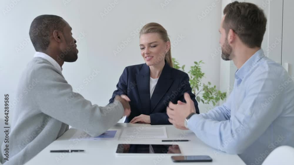 Mixed Race Business People Shaking Hands while Discussing Documents