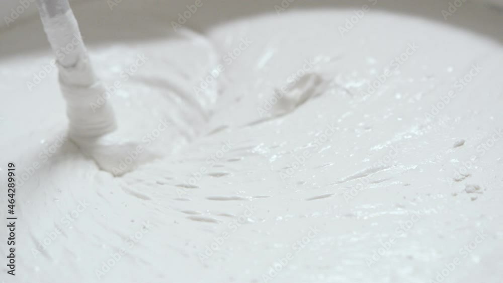White finishing putty is mixed in a bucket White finishing putty is mixed in a bucket