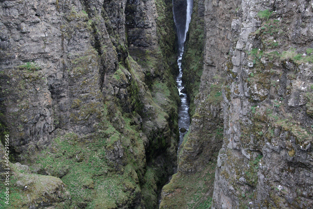 wąski wodospad glymur w islandii spływający po omszonych skałach