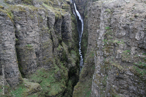 wąski wodospad glymur w islandii spływający po omszonych skałach photo