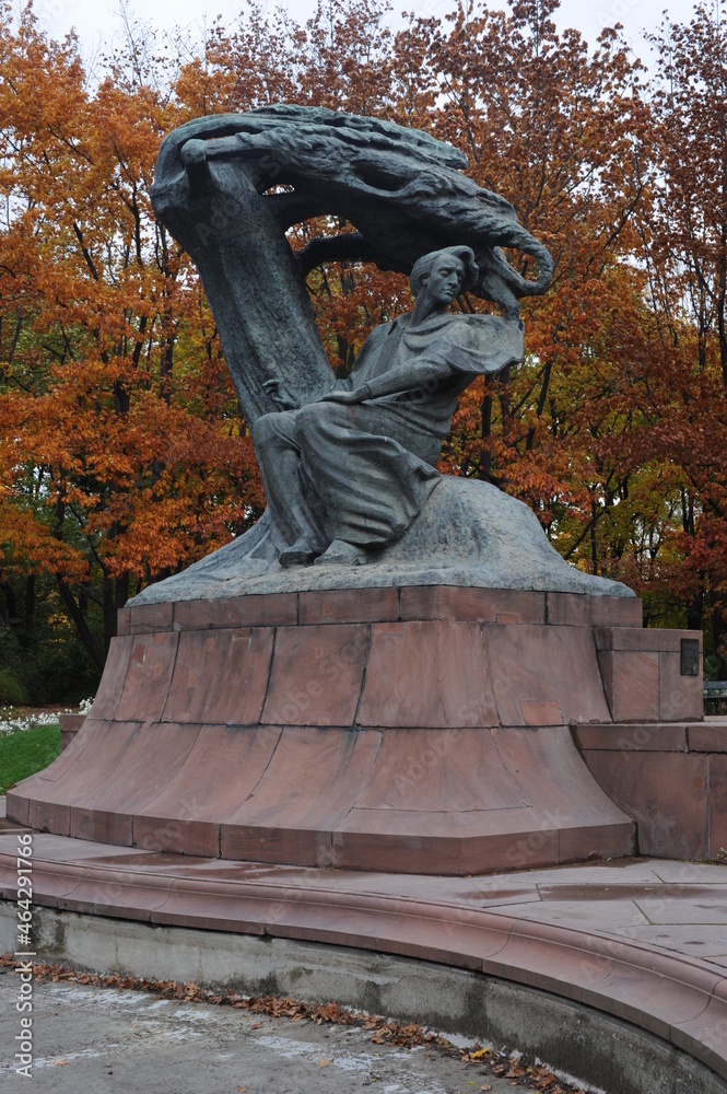 Naklejka premium Frederic Chopin statue monument in Lazienki (Royal Baths) Park in Warsaw, Poland in autumn with foilage on the trees