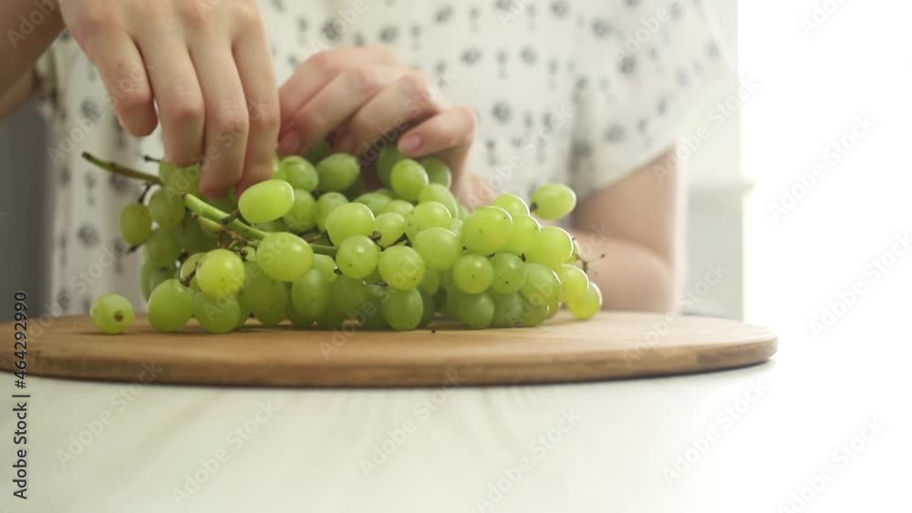 Young girl eat green grapes on table at kitchen, healthy food concept Young girl eat green grapes on table at kitchen, healthy food concept