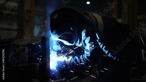 A welder in a helmet is working at the plant photo